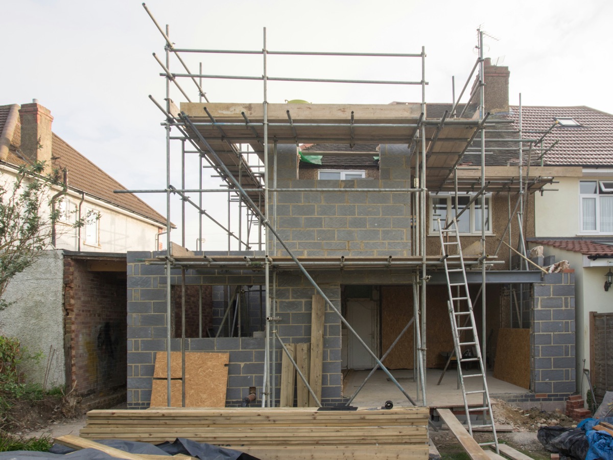 Independent house under construction with scaffolding and blockwork, showing structural stage of building an independent floor in Delhi